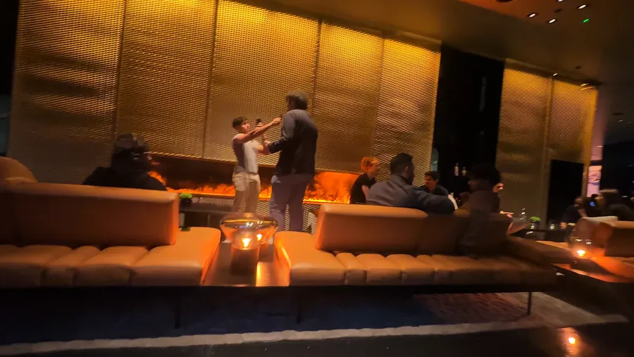 Founders on long amber-lit sofas in front of a fire wall